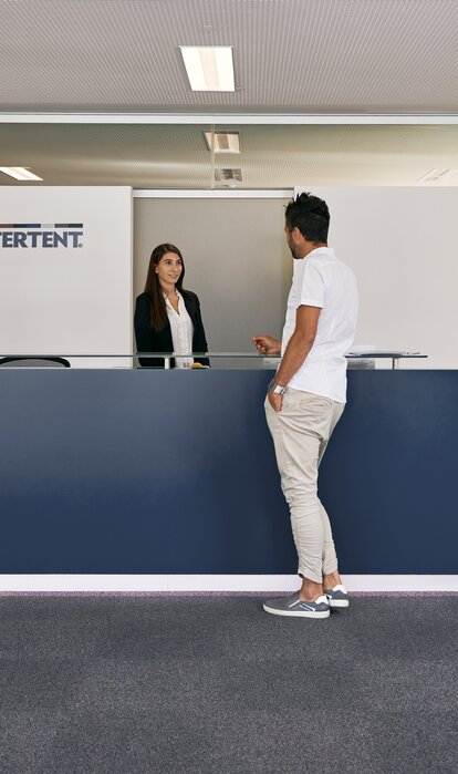 Die Rezeptionistin empfängt den Kunden im Eingangsbereich des MASTERTENT Headquarters.