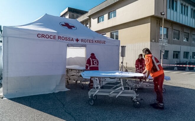 The Red Cross staff carries the corona patient to the rescue tent. The Rescue Kit tent is white. 