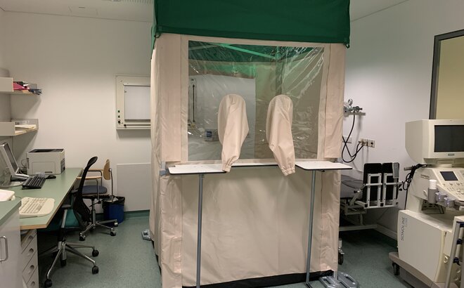 Piccolo gazebo pieghevole bianco e verde 1,5x1,5 con pareti laterali. Il gazebo viene utilizzato in uno studio medico per test clinici sul covid19