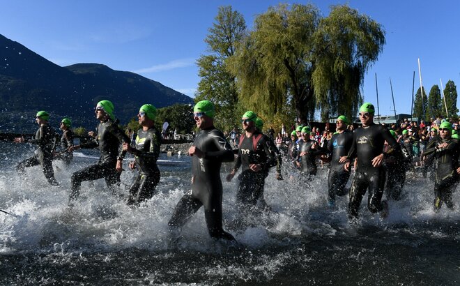 Los atletas que participan en un triatlón corren hacia el agua.